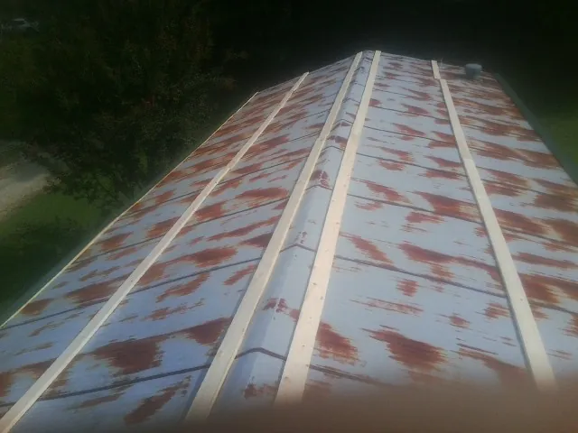 Rusted metal roof panels with new wood purlins before replacement — Storm Damage Roof Repair in New Albin by Roofing Brothers