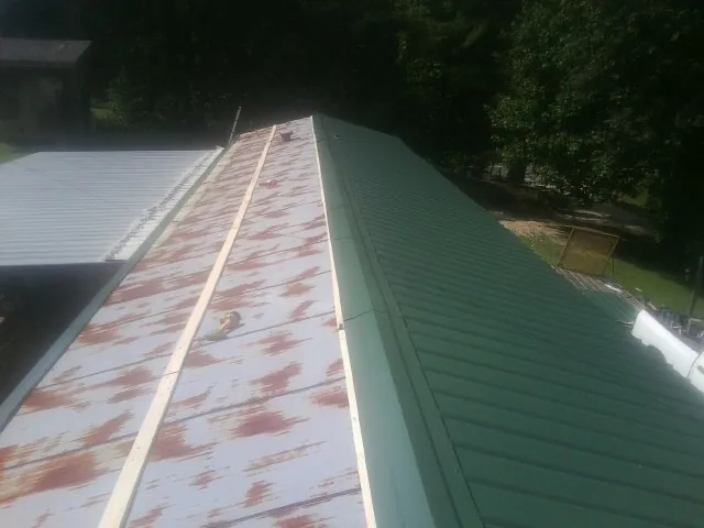 Old rusted panels beside newly installed green metal roofing — Wind Damage Roof Repair by Roofing Brothers in New Albin