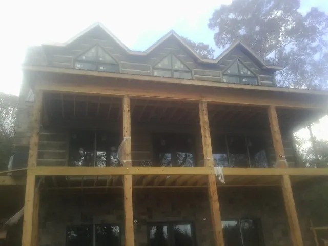 Dormers and porch framing on a large log home under construction — Roof Coating work by our crew in New Albin