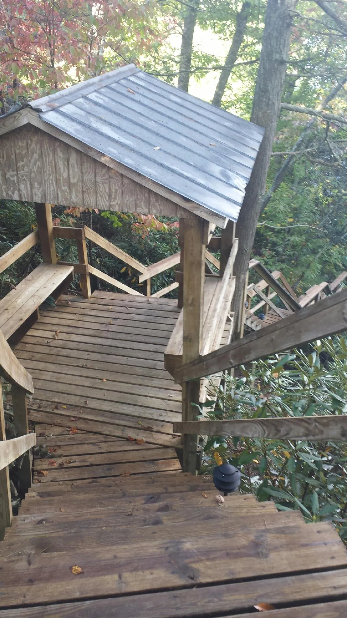 Metal roofed shelter over wooden steps on a wooded walkway — Skylight Repair & Installation work by our crew in New Albin