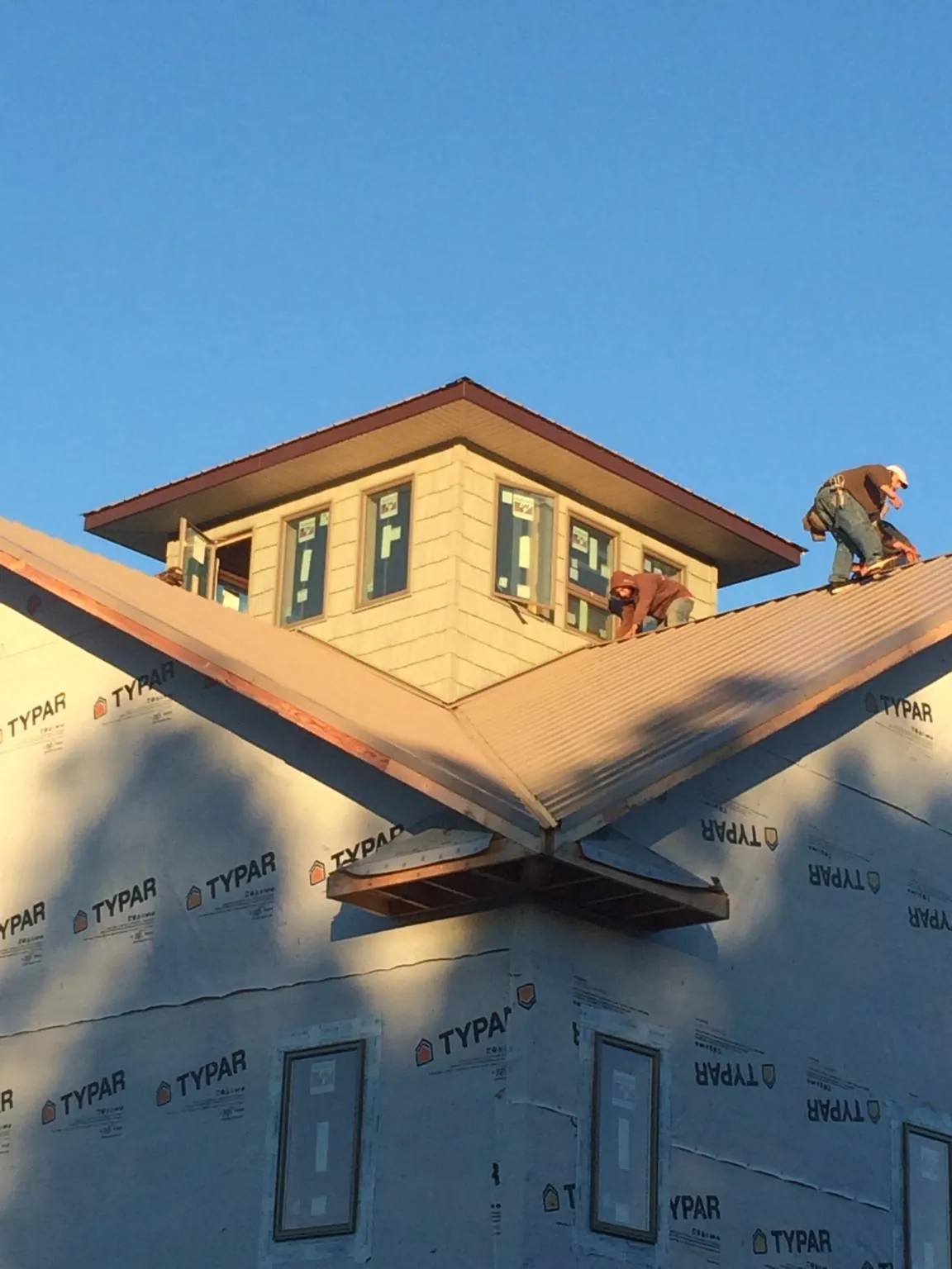 Roofers working around a rooftop cupola on a new metal roof at sunset — Roof Waterproofing in New Albin by Roofing Brothers